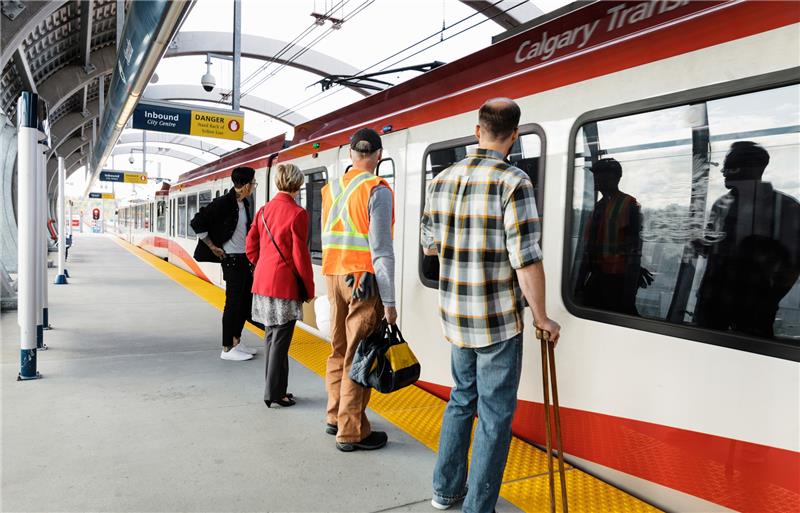 A row of several people waiting to enter a CTrain